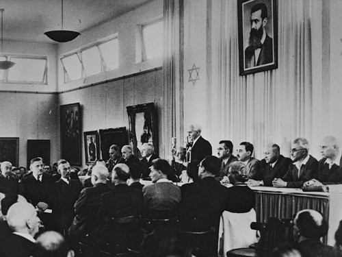 David Ben-Gurion reading the Declaration of Independence under a portrait of Theodor Herzl, 14 May 1948